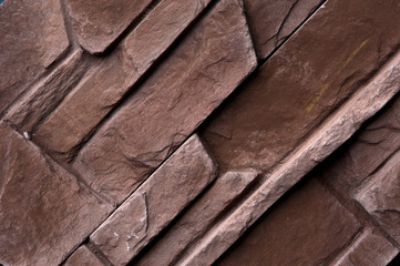 Stone wall of natural stones in different sizes. Rustic stone veneer in shades of brown color. Wall covering with natural stones