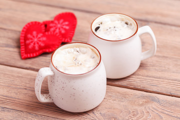 Background of romantic mood. Two cups of coffee and decorative hearts on a blurred background, on Valentine's Day or Birthday, wedding day. Wooden background. Selective focus, close-up, copy space