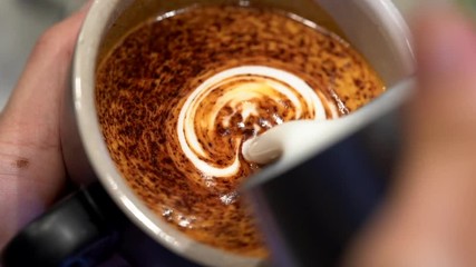 Barista pouring milk into coffee