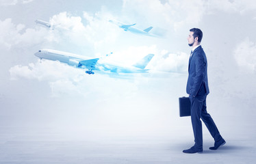 Obraz premium Elegant businessman going somewhere with briefcase and airplane on the background 