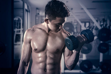 Fototapeta na wymiar Muscular man exercising with a dumbbell
