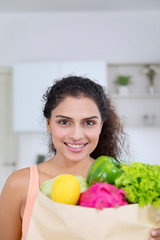 Pretty girl holds a paper bag with vegetables