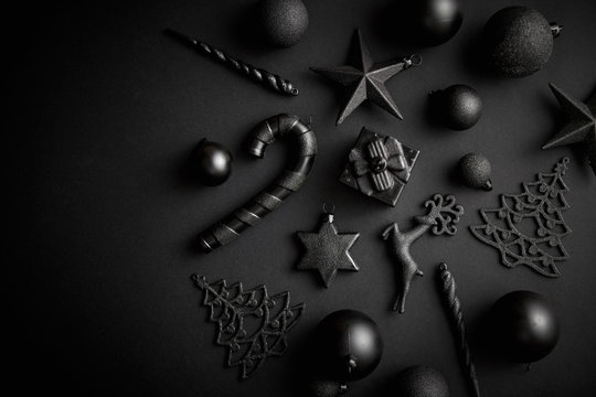 Christmas minimalistic and simple composition in mat black color. Christmas gifts, decorations on black background. Flat lay, top view with copy space