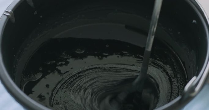 Slow motion closeup mixing black ink to micro concrete plaster