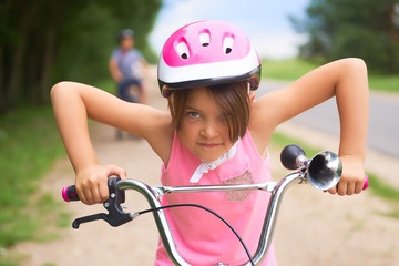 Naklejka premium Portrait of a litte girl in a pink safety helmet driving her bike.