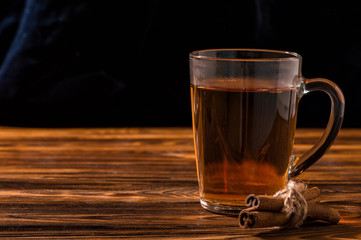 Close up. Black aromatic tea in a glass transparent cup. Rustic brown wooden background.