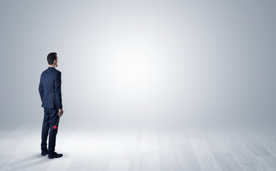 Obraz premium Man standing with his back in an empty room with object in his hand