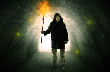 Ugly man with burning flambeau walking in a dark tunnel