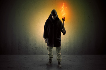 Ugly scary man with burning flambeau walking in an empty space