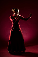 Fototapeta premium Lady in red gown standing and posing in studio. Portrait of beautiful elegant woman in evening dress