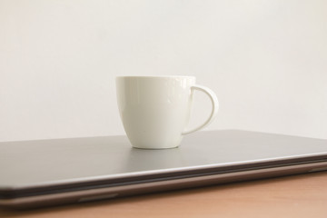 White coffee cup on wood table with copy space on white wall background.