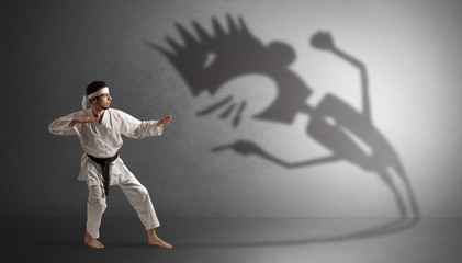 Fototapeta na wymiar Young karate man fighting with a big black scary shadow 
