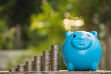stack of coins with blue bear piggy bank on green background,saving money concept.