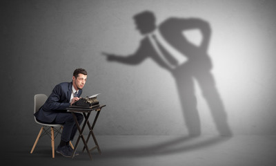 Little man working and a big shadow arguing with him

