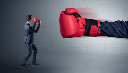Tiny businessman fighting with boxing gloves
