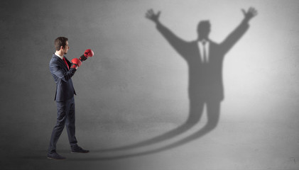 Fototapeta premium Businessman with boxing gloves fighting with disarmed businessman shadow 
