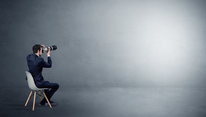 Businessman staying in an empty grey dark room with stuffs on his lap
