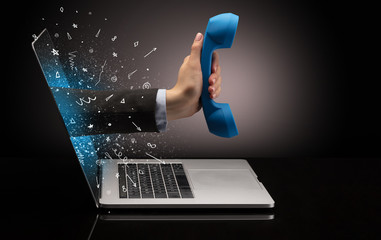 Hand with vintage phone coming out of a laptop with sparkling effects
