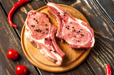 Raw pork on wooden table with salt and pepper