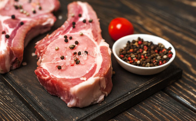Raw pork on wooden table with salt and pepper
