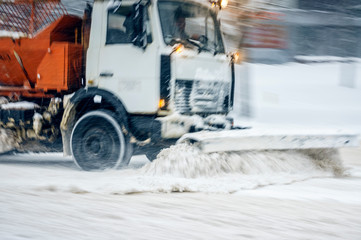 Snow plow truck removes snow from the city road. Snowstorm in the city - seasonal abstract motion...