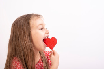 Cute little girl with a heart lollipop