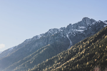 Beautiful view of snowy Alp mountains and green coniferous trees hill under the blue november sky, with place for text. Autumn sunny day in the Alps, Chamonix, France