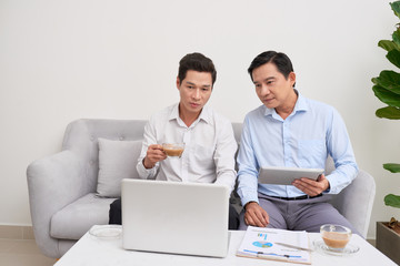 Cheerful atmosphere. Two businessman sitting in front of laptop talking about their plans.