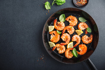 Fried fresh shrimps with spices on black pan