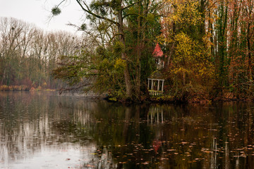 Petit kiosque ou gazébo sous une averse de pluie au bord d'un bois sur les berges d'un étang en...