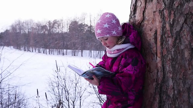 little girl draws a winter landscape in the forest