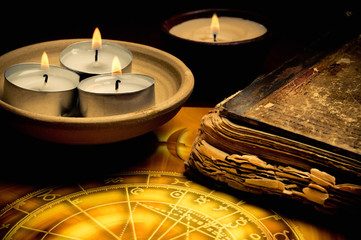 Esoteric mystical atmosphere with candles, old book and zodiac