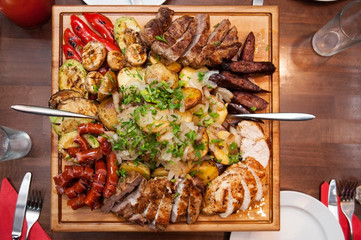 Delicious food baked on fire - potatoes with lard and onions, sausages, steaks, fillets and...
