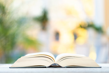 Large open hardcover book on a bright interior room background