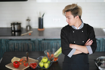 Asian cook in the kitchen prepares food in a cook suit