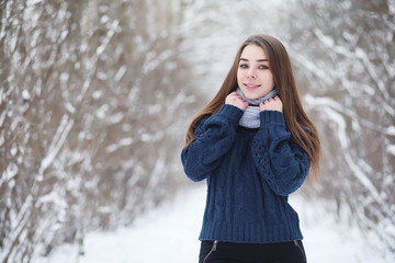 A young girl in a winter park on a walk. Christmas holidays in the winter forest. The girl enjoys winter in the park.