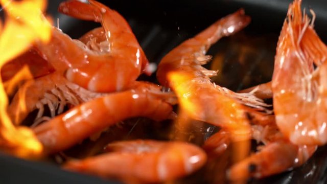 Super slowmotion footage of throwing fresh prawns and seasoning on ignited pan, 1000fps 4k