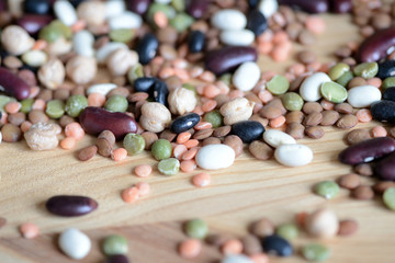 Mix of different beans on wooden background close up