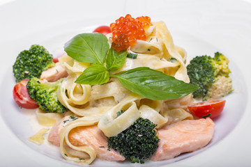 Pasta with salmon, broccoli, tomatoes and red caviar in cream sauce 
