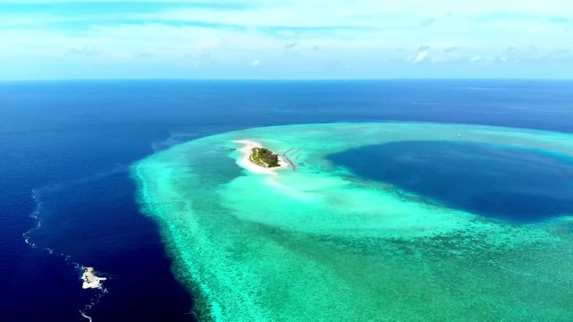 Aerial: Flying over idyllic atoll, scenic travel destination Maldives Polinesia. Blue lagoon and turquoise coral reef. Shot in Wakatobi National Park, Indonesia