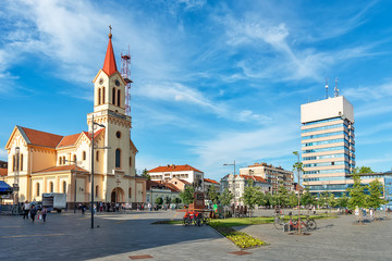 Fototapeta na wymiar Zrenjanin, Serbia - May 17, 2018: Zrenjanin downtown, city architecture, urban landscape. Square of freedom with Cathedral of St. John of Nepomuk and a monument of King Petar Karadjordjevic the first.