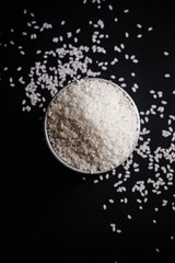 Arborio rice in metallic tin on black background. Overhead view