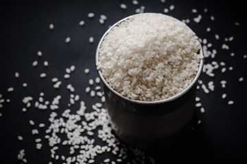 Arborio rice in metallic tin on black background. Overhead view