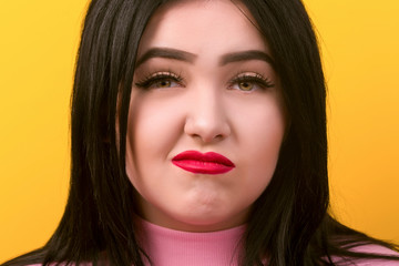 portrait of a crooked displeased size model plus close-up on yellow background