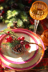 Serving Christmas or new Year's table. Plates with a red edge on the background of fir branches and a glass. Interior design.