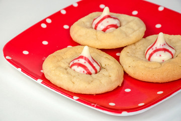 close up of sugar cookies with red striped white chocolate candy on polka dot plate