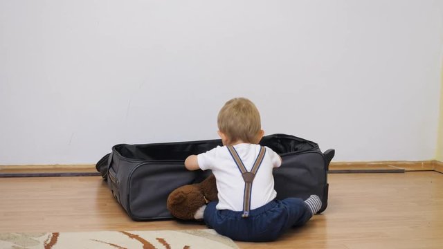 Baby child back with suspender investigate traveling suitcase, look for present