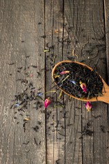Dry tea in wooden plates, on wooden background. Leaves of red, green and black tea. Macro photo.