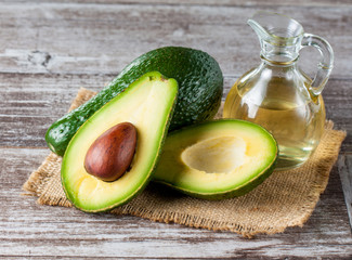 Close-up of an avocado and avocado oil on wooden table. Healthy food concept.