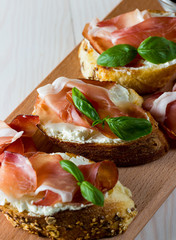 Italian tomato, prosciutto, jamon, ham and cheese bruschetta. Tapas, antipasti with chopped vegetables, herbs and oil on grilled ciabatta and baguette bread.